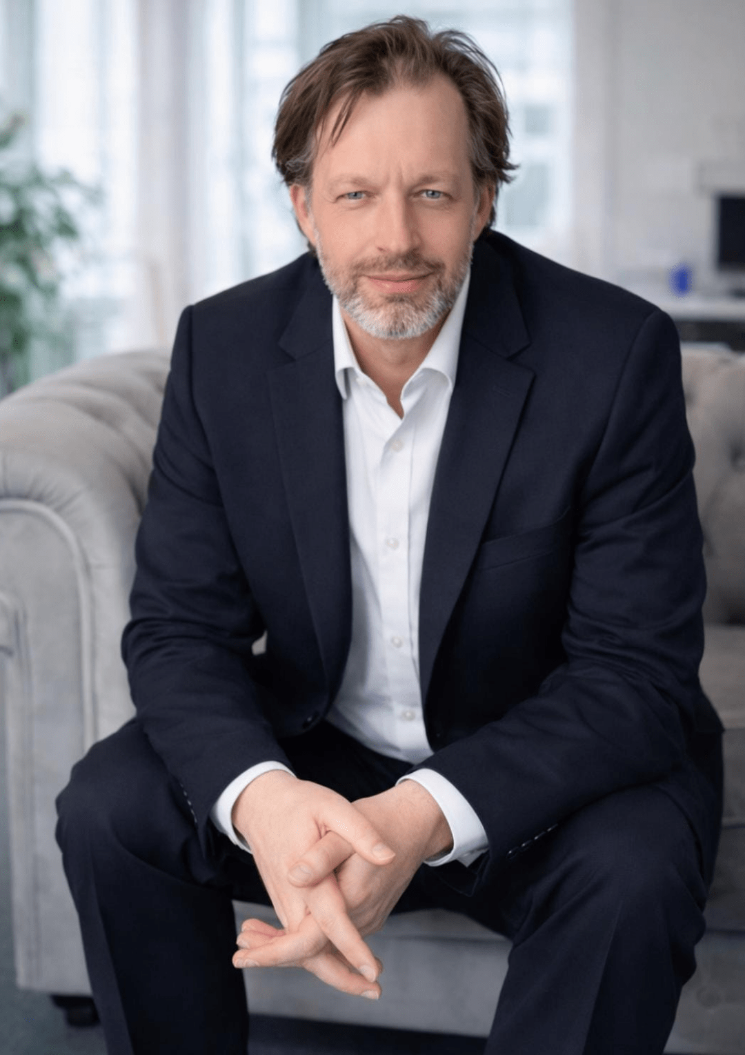 Mann im Anzug auf Sofa in freundlicher Wohnatmosphäre